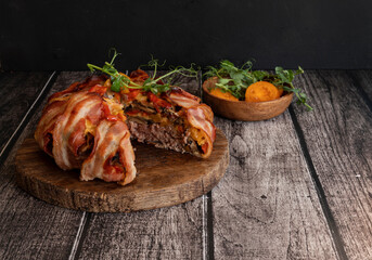 Minced meat baked in bacon. Meat pie with bacon on a dark wooden background.