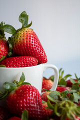 Heap of ripe fresh strawberries in cup on white background