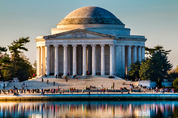 spring morning sunlight illuminating Thomas Jefferson Memorial in Washington DC with crowd of people on the steps.