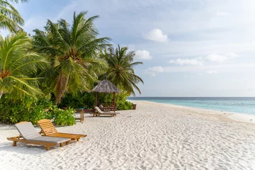 Tuinposter Traumhafter Strand mit Palmen und Sonnenliegen auf einer kleinen Insel auf den Malediven © Lars