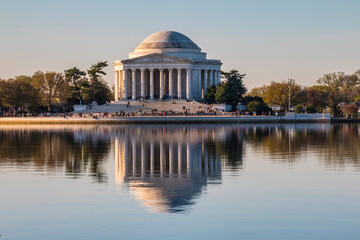 Cherry blossoms tree during spring time lined up in Washington DC's river bank. The Thomas Jefferson Memorial on the background.