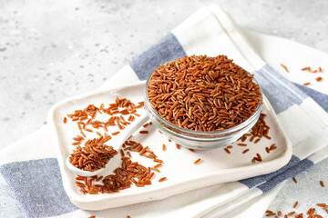 Red rice in a glass bowl on the light gray kitchen table. Red rice on a light background
