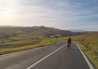 Fototapeta premium Ciclista su strada nelle colline della campagna toscana