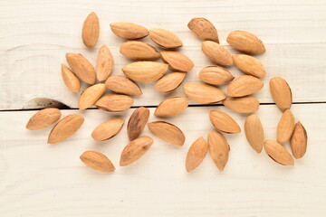 Unpeeled organic dried almonds, close-up, on a wooden table.