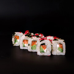 Roll with red caviar and sesame seeds on a black background