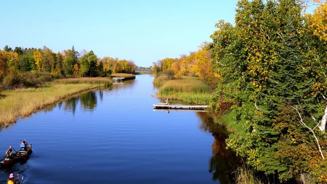 Mississippi River and two canoes head north toward Bemidji Minnesota near highway 2 with zoom in. Beautiful autumn colors in the trees along the river, a few miles from the source at Lake Itasca