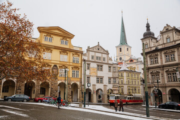 Renaissance Sternberg Palace and spire of baroque Church of St. Tomas at Lesser Town Square, Malostranske namesti, snow in winter day, Mala Strana district, Prague, Czech Republic