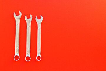 Steel spanners of different sizes and diameters on red background. Set of chrome vanadium wrenches. Metallic repair tool for car, plumbing, machines. Flat lay, toy view. Copy space. 