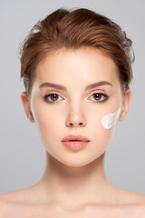 Obraz premium Spot of cosmetic cream on a woman's face. Beautiful face of young caucasian woman with perfect healthy skin, isolated. Pretty white model caring of face.