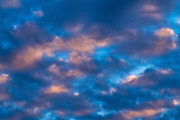Naklejka na ściany i meble Amazing clouds in blue sky, illuminated by rays of sun at sunset to change weather. Soft focus, motion blur colorful abstract cloudscape background.