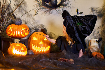 Halloween cute little girl dressed as a witch and a witch with a magic wand. Pumpkins and cobwebs....