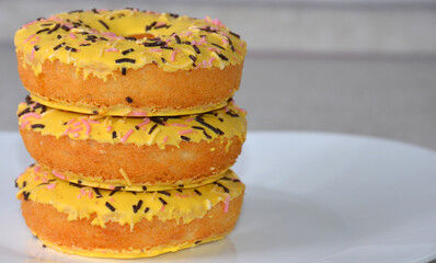 Yellow donuts on a white plate.
