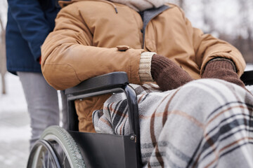 Close-up of African man sitting in wheelchair covering with warm blanket during his winter walking