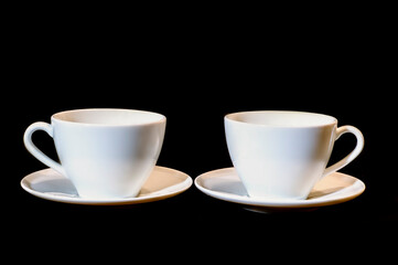two white ceramic cups on a black background
