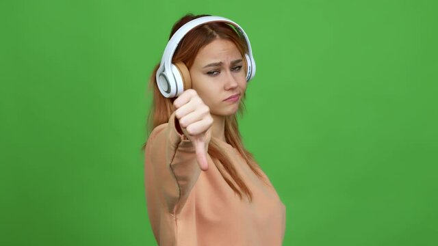 Teenager girl listening music with headphones doing bad signal over isolated background