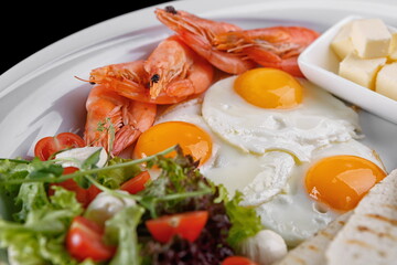 Breakfast fried eggs salad croutons bread butter greenland prawns on a white plate
