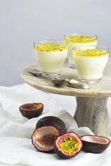 Italian dessert panna cotta in a glass cups with fresh passion fruits on a cake stand.