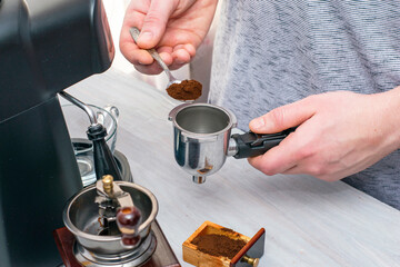 a person makes coffee in a coffee machine pours ground coffee into the dispenser with a spoon