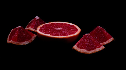 Red grapefruit parts on dark background