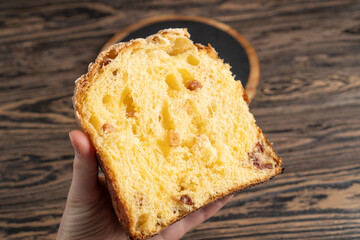 Homemade Panettone. Slices of homemade dessert cake in hand. Easter cake on brown wooden table