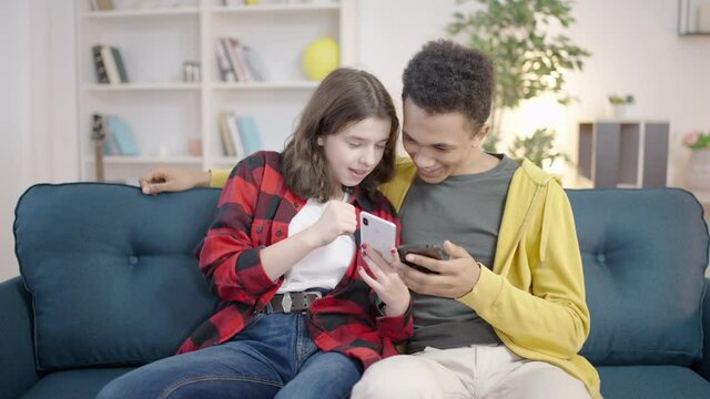 Couple of teenagers testing new social media app on smartphones, feeling excited
