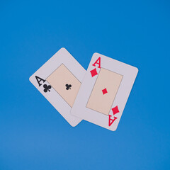 Two playing cards showing aces of clubs and diamonds on blue background