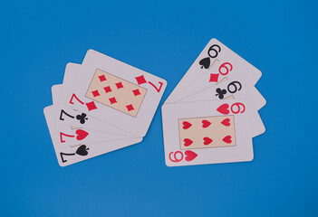Playing cards showing seven and six for hearts, clubs, spades and diamonds on blue background