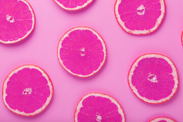 Obraz na płótnie Canvas Grapefruit slices on a pink background with a pattern in the form of a pattern.
