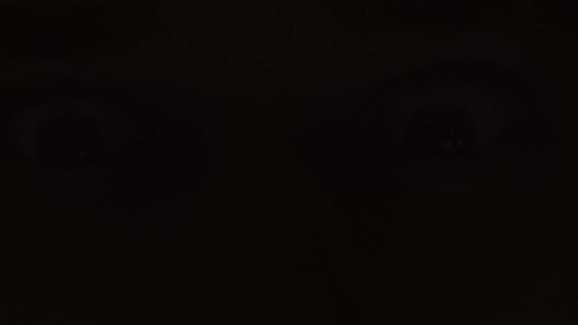 Angry look of a man in the dark with flashes of lightning, close-up.