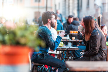 Hipster friends drinking coffee in Stockholm old town - Young couple sitting face to face outdoors and enjoying time together  - 410975316