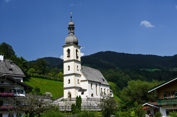 Fototapeta na wymiar The church of St. Sebastian in the national park Berchtesgaden, Bavaria, Germany. The church is standing in a valley surrounded by forested hills.