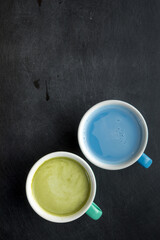 Obraz na płótnie Canvas Cup of blue matcha latte and green matcha latte on black scribbled background