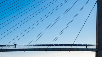 Dos personas corriendo por un puente colgante en un dia soleado de invierno
