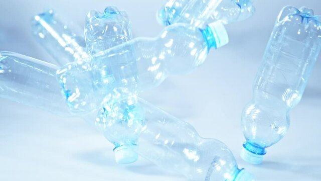 Super Slow Motion Shot of Falling Empty Plastic Bottles on Blue Gradient Background at 1000fps.