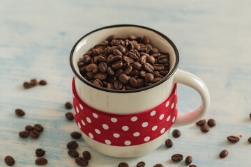 White cup full of coffee beans with red dotted tape on light blue