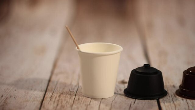 Taza de caf&eacute; con c&aacute;psulas sobre mesa de madera.