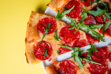 hand holds pizza, tearing off a slice on a colored background