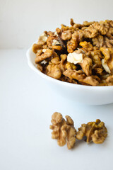 shelled walnuts in a white ceramic plate on a white background