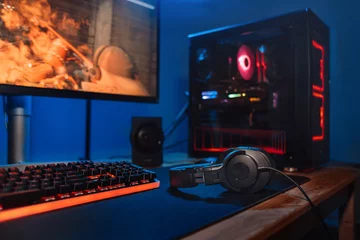 Fotobehang Gaming Computer gamer workplace with new game keyboard, mouse, headphones, modern pc with blur blue and red neon light. Powerful personal computer for e cyber sport gamer on the table at home. Close up  © Arsenii