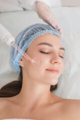 Beautiful young woman receiving darsonval procedure electric massage at beauty salon. Hardware cosmetology. Selective focus.