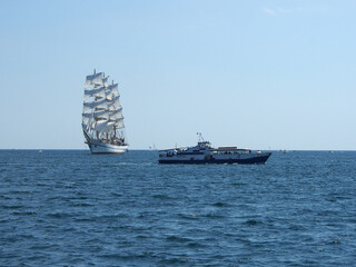 A sailing ship with white sails on three masts at sea. The concept of a cruise, vacation at sea,...