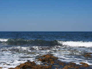 The sea wave runs on the shore. A foamy sea wave rolls over the rocky shore, close-up, seascape.