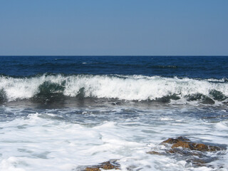 The sea wave runs on the shore. A foamy sea wave rolls over the rocky shore, close-up, seascape.