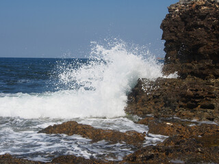 Fototapeta na wymiar The sea wave runs on the shore. A foamy sea wave rolls over the rocky shore, close-up, seascape.