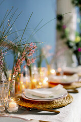 Decorated table ready for dinner. Beautifully decorated table set with flowers, candles, plates and serviettes for wedding or another event in the restaurant. Red and rose flowers on grass.