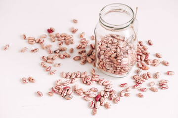 Obraz na płótnie Canvas Dry beans in a glass jar scattered on a white table background. Copy, empty space for text
