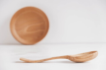 Empty wooden bowl and wooden spoon on a white table background. Copy, empty space for text