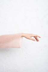 Hands with manicure in a pink sweater on a white background