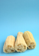 Three loofah sponges on a blue background. Vertical copy space.