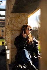 Portrait of young redhead woman listening music with headphones outdoors